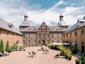 Dziedziniec zamku Hugenpoet w Essen Zabytkowy zamek z dziedzińcem w Essen, otoczony przyrodą, oferuje miejsca do siedzenia na świeżym powietrzu.