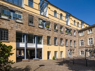 Buitenkant Gevelzicht van een historisch gebouw van gele en bruine steen, met een binnenplaats met gele muren.