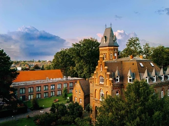 Marienburg Monheim with a view of Monheim am Rhein The Marienburg Monheim features historic red brick architecture surrounded by trees.