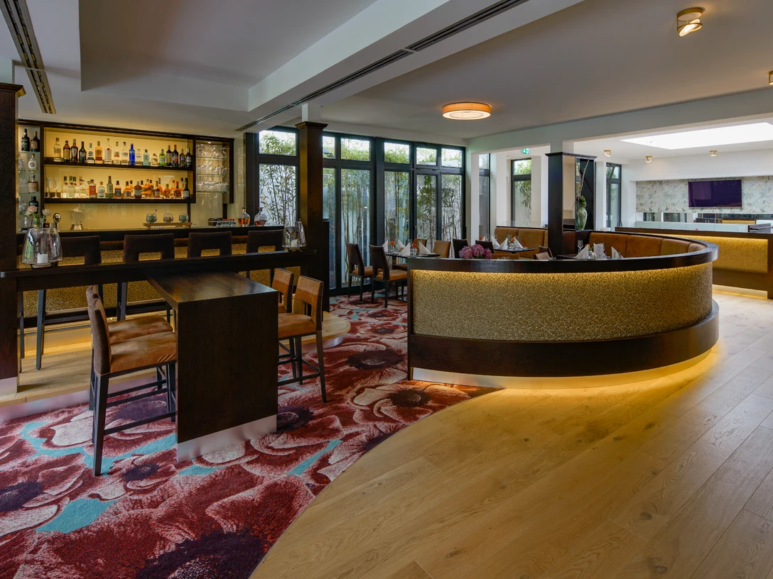 Interno del ristorante Merk.Mahl Interni di un ristorante moderno con un elegante bar, pavimento in legno e un tappeto con un motivo raffinato.