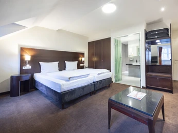 Pokoje hotelowe w hotelu Fletcher Hotel-Restaurant Waldhotel Nadrenia Północna-Westfalia Pokój dwuosobowy z dwoma pojedynczymi łóżkami, lampkami nocnymi, szafą i widokiem na łazienkę.