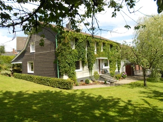exterior view A charming, ivy-covered house in the middle of a green garden and bright sunshine.