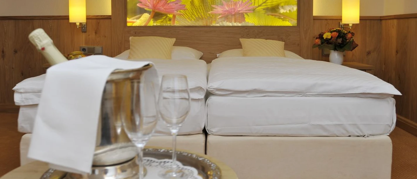 Gronauer Tannenhof Two single beds in a hotel room, decorated with yellow cushions, floral picture on the wall.