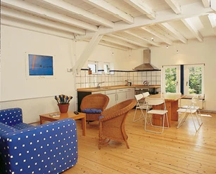 woonkamer Lichte woonkamer met houten vloer, eettafel met witte stoelen, blauwe bank en rotan fauteuils.