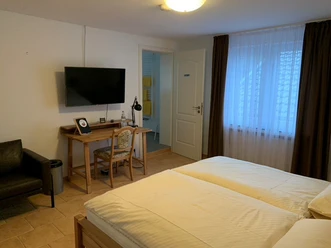 The Fairytale Forest Hotel Bright hotel room with double bed, desk, television, armchair and adjoining bathroom.