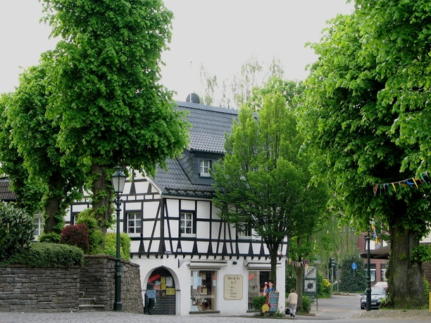 Lindlar town center Timber-framed house with slate roof in green surroundings, a colorful garland and a lamppost on the right.