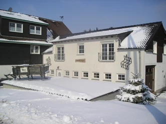 OLYMPUS DIGITALE CAMERA Een met sneeuw bedekt gebouw van twee verdiepingen met witte gevels en donkere daken in de winter.