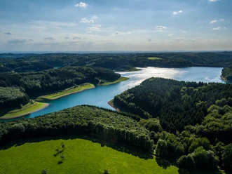Grote Dhünn Dam Panoramisch uitzicht op een uitgestrekt landschap met meren, bossen en groene weiden onder een blauwe hemel.