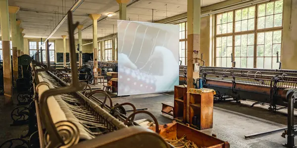 Historische Industriemaschinen in alter Tuchfabrik mit großem Fenster.