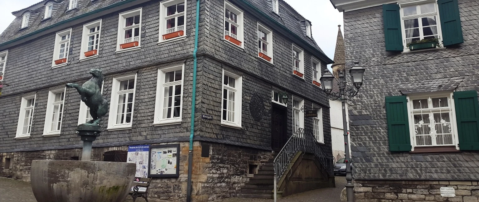 Vue extérieure de l'ancienne mairie et de la maison historique de la ville de Mettmann Ancien bureau du maire et maison historique de la ville de Mettmann avec statue et panneau d'information au premier plan.