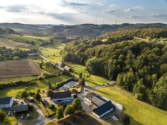 Hypermétropie à Elfringhauser Suisse Paysage d'Elfringhausen en Suisse avec des collines ondulantes, des forêts et des bâtiments isolés sous un ciel bleu.