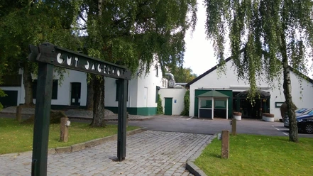 Gut Jägerhof in Erkrath Ingang met boogbrug naar Gut Jägerhof in Erkrath, omgeven door groen en een verhard pad.