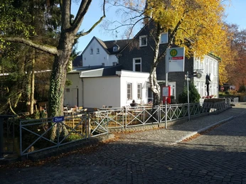 Przystanek autobusowy bezpośrednio przy Palazzo Wiedenhof w Haan Przystanek autobusowy w Haan, naprzeciwko zabytkowego Palazzo Wiedenhof, otoczonego jesiennymi drzewami.