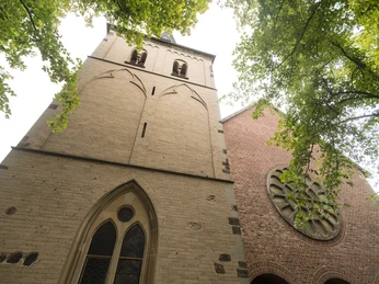 Chiesa di San Gereone a Monheim am Rhein La chiesa di San Gereone a Monheim am Rhein con la sua imponente torre e le finestre gotiche, circondata da alberi.