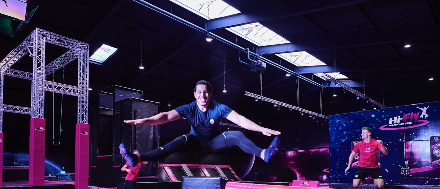 Hi-Fly trampoline park in Hilden A trampoline park with bright pink elements and people jumping happily and having fun.