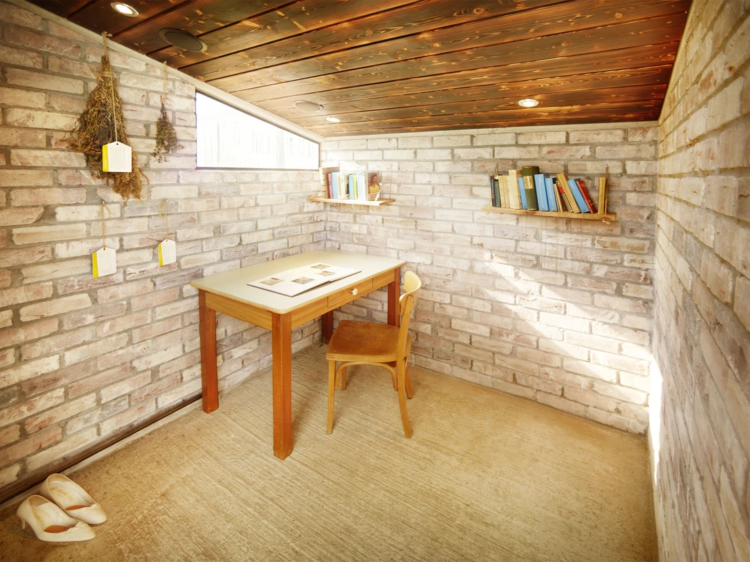 Hilla'nın Monheim am Rhein'deki okuma kulübesi Monheim am Rhein'daki Hilla's Reading Shed, masa, sandalye ve raflarla davetkar bir okuma köşesi sunuyor.